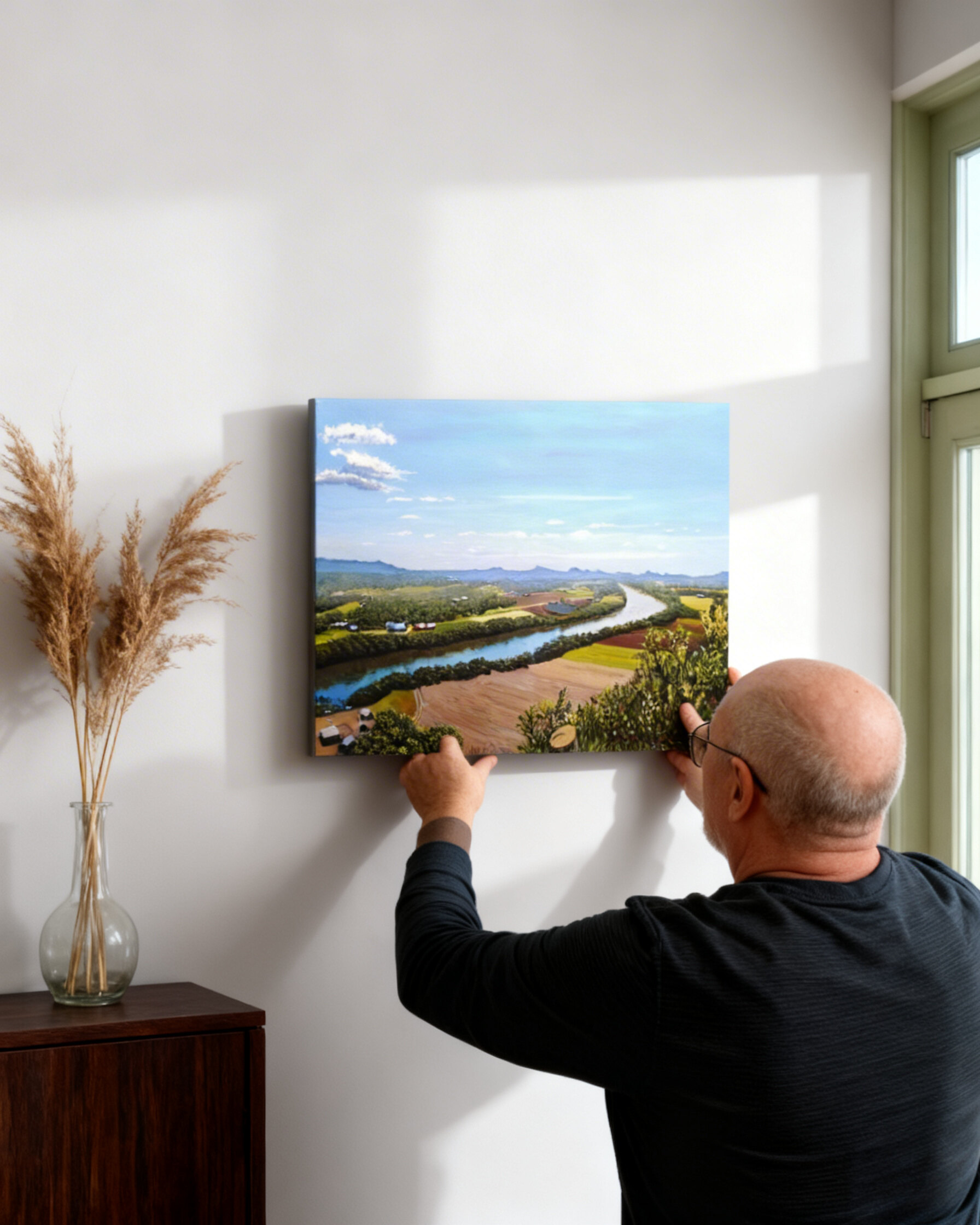 Artist hanging "The Valley's River" painting